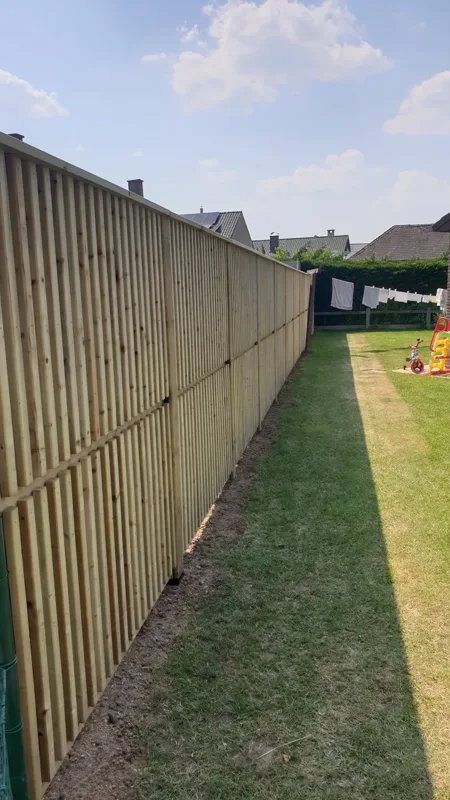 Verticale houten afsluiting langs een gazon